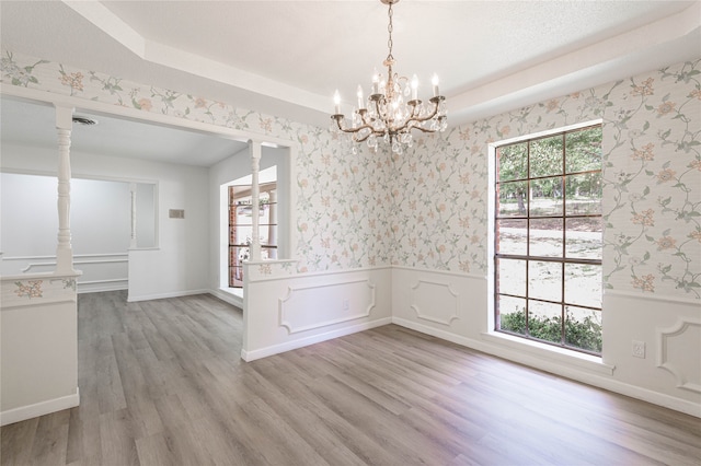 unfurnished dining area featuring a wealth of natural light, a chandelier, and light hardwood / wood-style floors