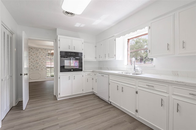 kitchen with oven, white cabinets, white dishwasher, light hardwood / wood-style flooring, and sink