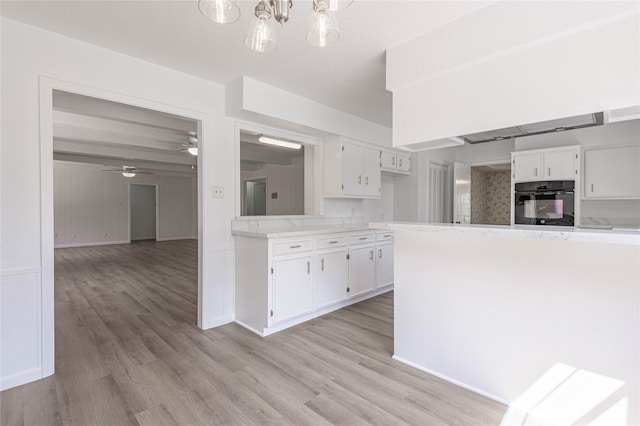 kitchen with oven, light hardwood / wood-style flooring, white cabinetry, and ceiling fan with notable chandelier