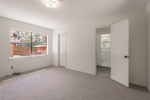 unfurnished bedroom with a textured ceiling and light colored carpet