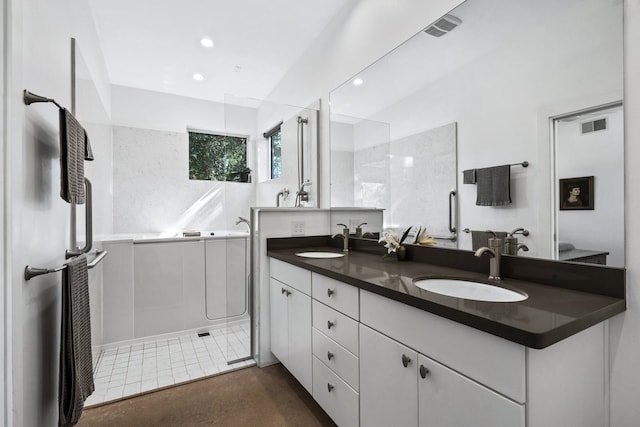 bathroom with vanity, a tile shower, and tile patterned flooring