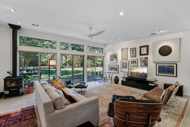 living room with a wood stove and ceiling fan