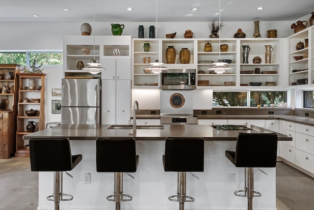 kitchen with a large island, sink, white cabinets, a kitchen bar, and appliances with stainless steel finishes