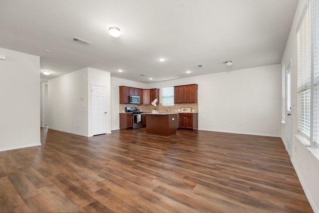 kitchen featuring appliances with stainless steel finishes, dark hardwood / wood-style floors, tasteful backsplash, and a kitchen island