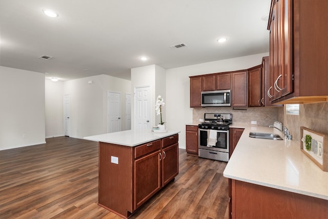 kitchen featuring decorative backsplash, stainless steel appliances, dark wood-type flooring, sink, and a center island