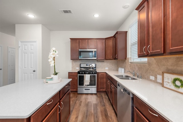 kitchen featuring decorative backsplash, dark hardwood / wood-style flooring, stainless steel appliances, sink, and a center island