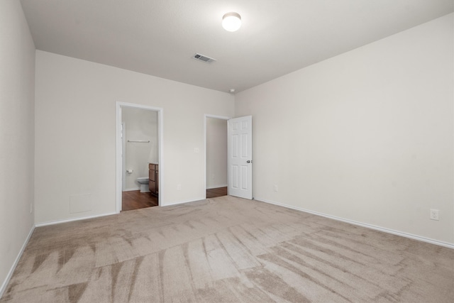 unfurnished bedroom with a spacious closet, light colored carpet, and a closet