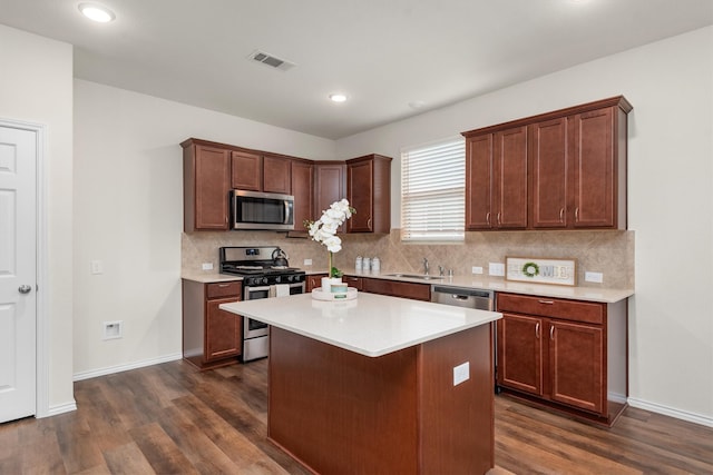 kitchen with decorative backsplash, appliances with stainless steel finishes, dark wood-type flooring, sink, and a center island