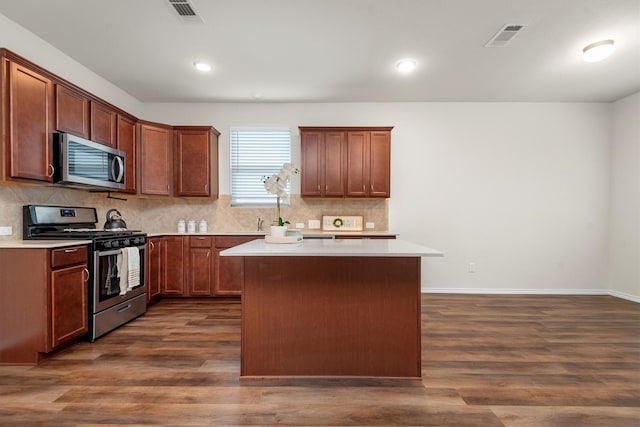 kitchen featuring appliances with stainless steel finishes, a kitchen island, and dark hardwood / wood-style flooring