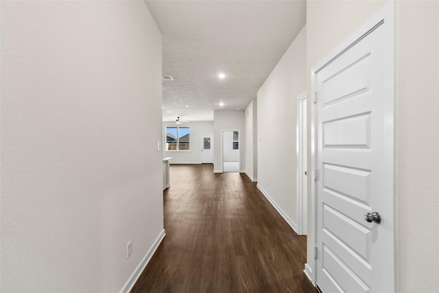 hall featuring dark wood-style floors, visible vents, recessed lighting, and baseboards