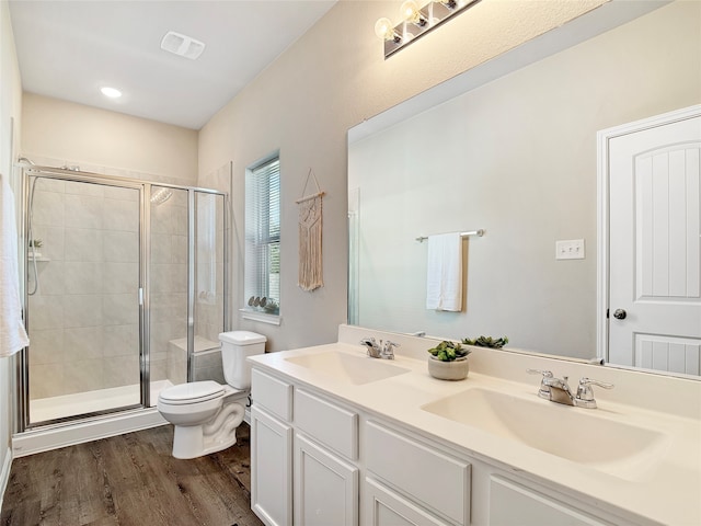 bathroom with vanity, a shower with shower door, hardwood / wood-style flooring, and toilet