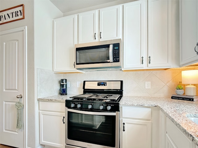 kitchen featuring appliances with stainless steel finishes, white cabinetry, and tasteful backsplash