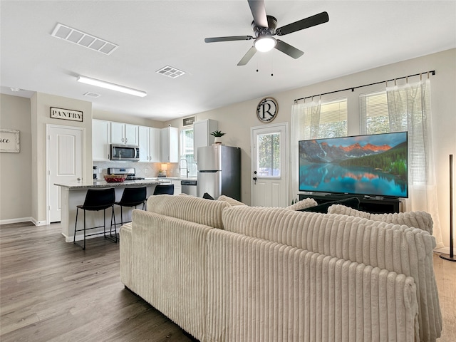 living room featuring ceiling fan, wood-type flooring, and sink