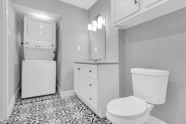 bathroom featuring vanity, stacked washer / drying machine, tile patterned flooring, and toilet