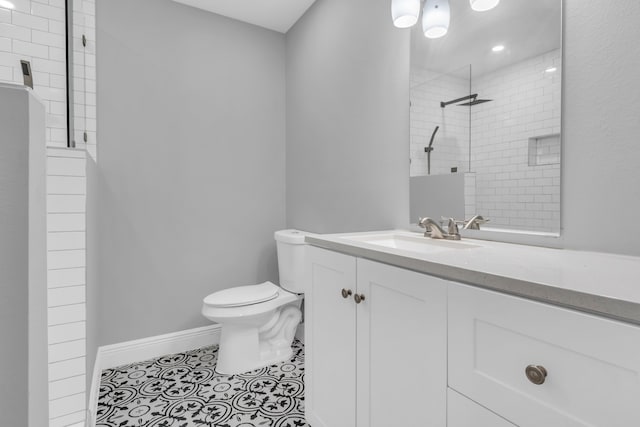 bathroom featuring tile patterned flooring, vanity, toilet, and tiled shower