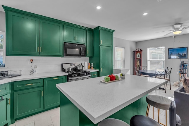 kitchen featuring tasteful backsplash, stainless steel range with gas cooktop, a center island, and green cabinetry