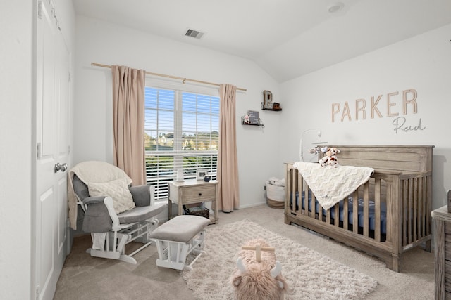 bedroom with a crib, carpet flooring, and vaulted ceiling