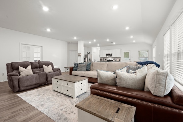 living room with a wealth of natural light, light hardwood / wood-style flooring, and lofted ceiling