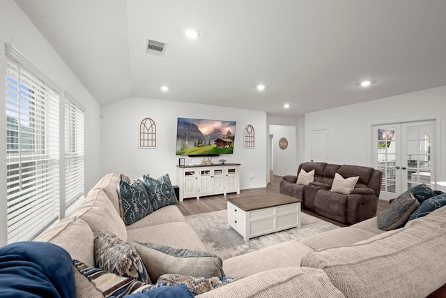 living room with light wood-type flooring, lofted ceiling, and french doors