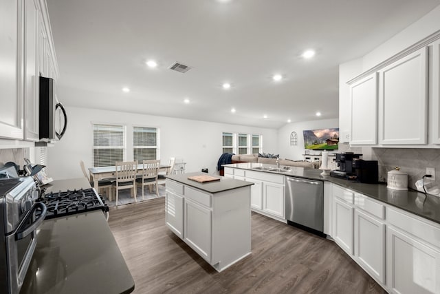 kitchen with stainless steel appliances, a kitchen island, dark hardwood / wood-style floors, sink, and white cabinets