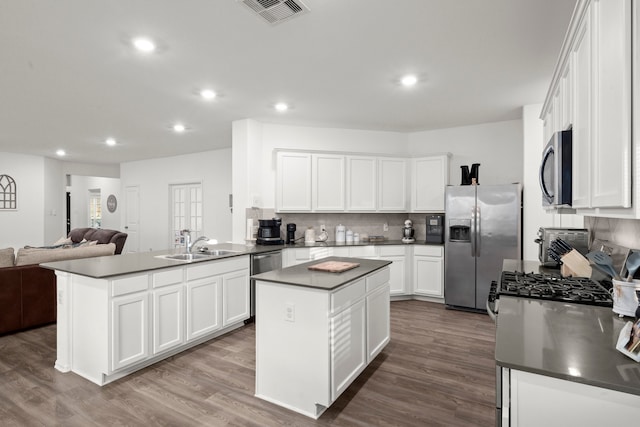 kitchen with white cabinetry, hardwood / wood-style floors, appliances with stainless steel finishes, and a kitchen island