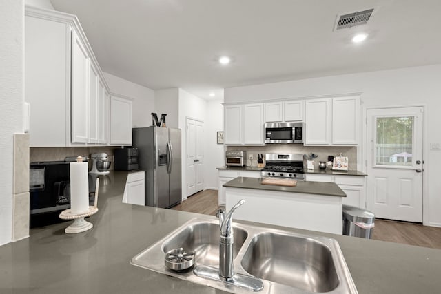 kitchen featuring stainless steel appliances, dark hardwood / wood-style flooring, sink, backsplash, and white cabinetry