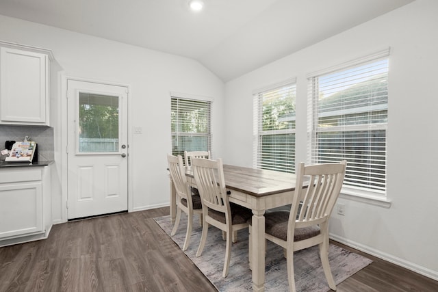 dining area featuring vaulted ceiling and dark hardwood / wood-style floors