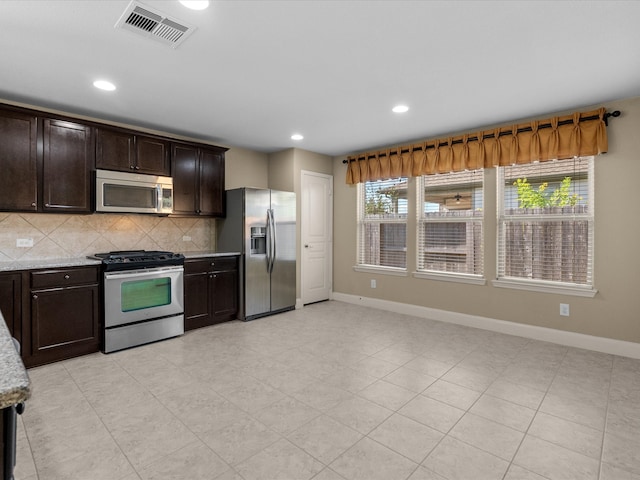 kitchen featuring backsplash, light stone counters, dark brown cabinetry, and stainless steel appliances