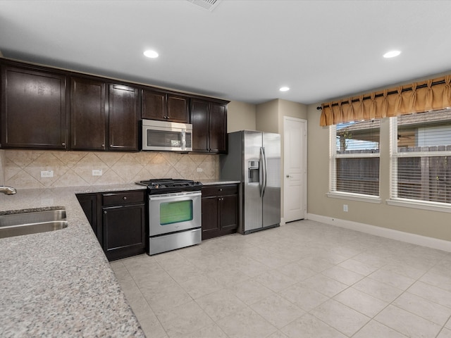 kitchen with backsplash, dark brown cabinetry, sink, and appliances with stainless steel finishes