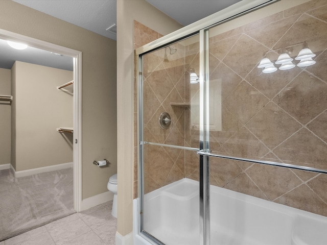 bathroom featuring a shower with door, tile patterned flooring, and toilet