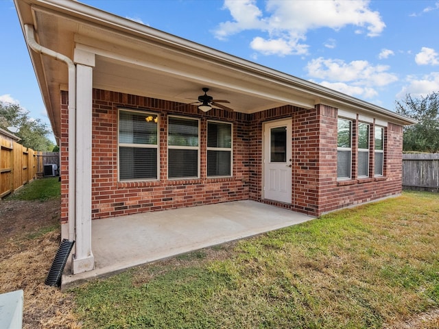 view of exterior entry featuring a yard, a patio, ceiling fan, and cooling unit