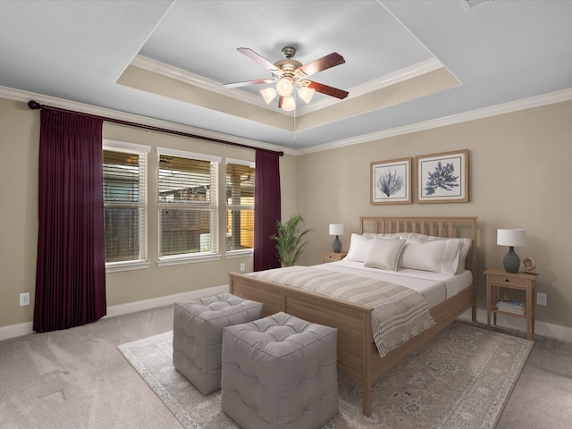 bedroom featuring light carpet, a tray ceiling, ceiling fan, and crown molding