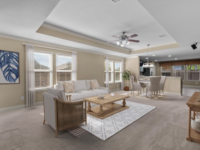 living room with ornamental molding, a tray ceiling, ceiling fan, and a healthy amount of sunlight