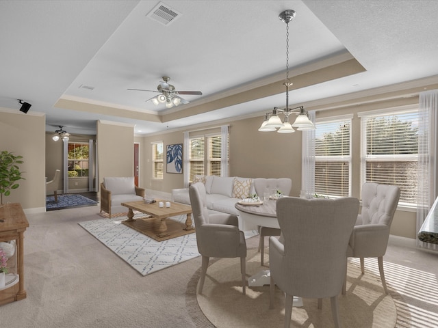 dining room featuring ceiling fan with notable chandelier, crown molding, light carpet, and a tray ceiling