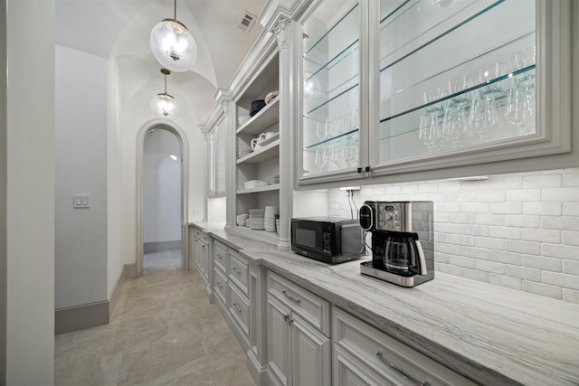 kitchen featuring light stone countertops, pendant lighting, and lofted ceiling