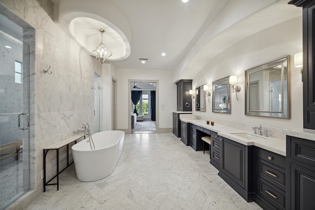 bathroom with vanity, shower with separate bathtub, an inviting chandelier, and tile walls