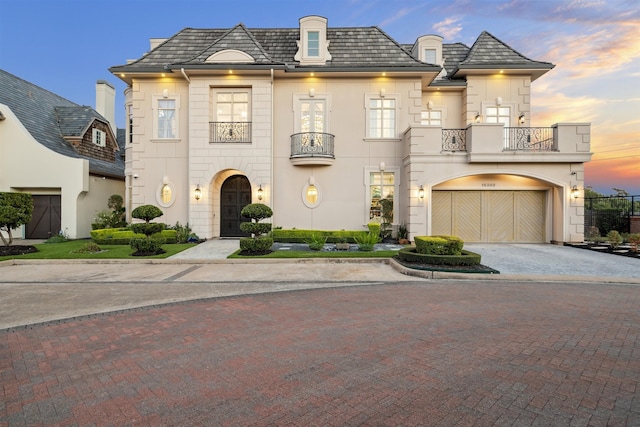 french provincial home with a balcony and a garage