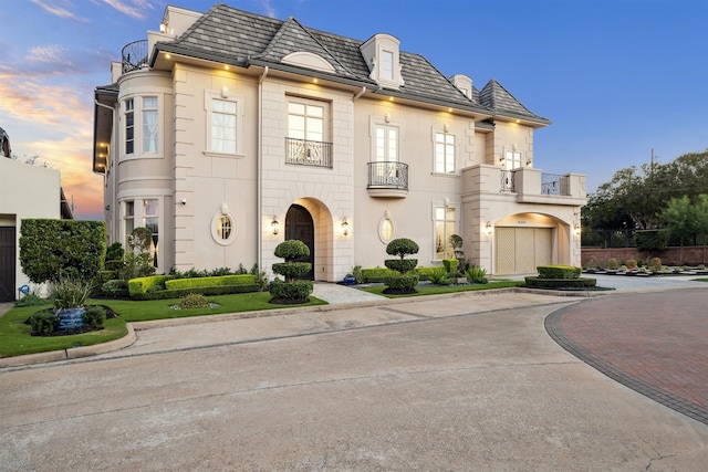 french country inspired facade with a balcony and a garage