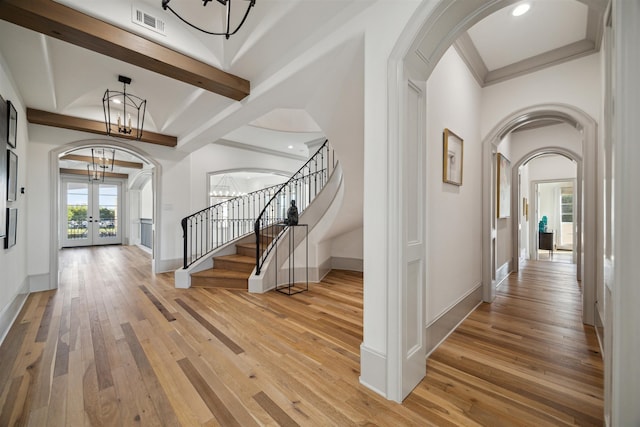 foyer with a chandelier, french doors, light hardwood / wood-style floors, and beam ceiling