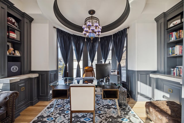 home office featuring light hardwood / wood-style floors, a notable chandelier, crown molding, and a tray ceiling