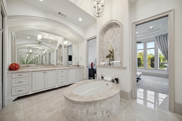 bathroom featuring a bathing tub, vanity, and a notable chandelier