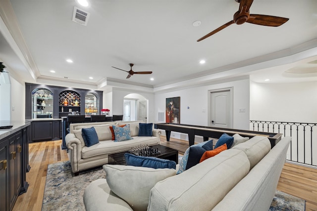 living room featuring ceiling fan, light wood-type flooring, and crown molding