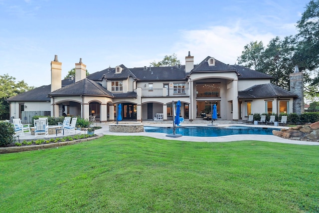 back of property featuring a balcony, a yard, and a patio