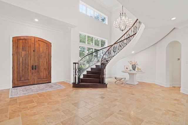 foyer with a towering ceiling, a notable chandelier, and ornamental molding