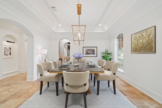 dining space featuring crown molding, a chandelier, and a raised ceiling