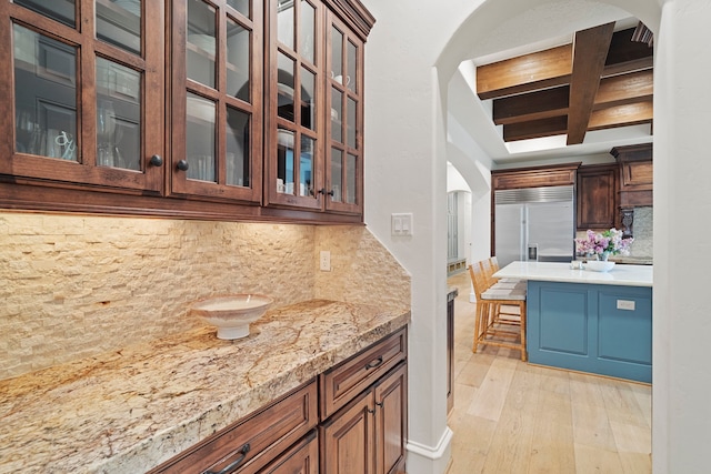 kitchen featuring light stone counters, tasteful backsplash, light wood-type flooring, and built in refrigerator