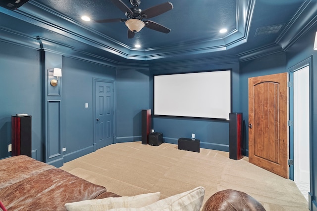 home theater room with crown molding, carpet floors, a tray ceiling, and ceiling fan