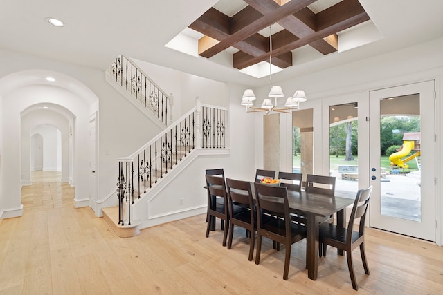 dining area with beam ceiling, coffered ceiling, a chandelier, and light hardwood / wood-style floors