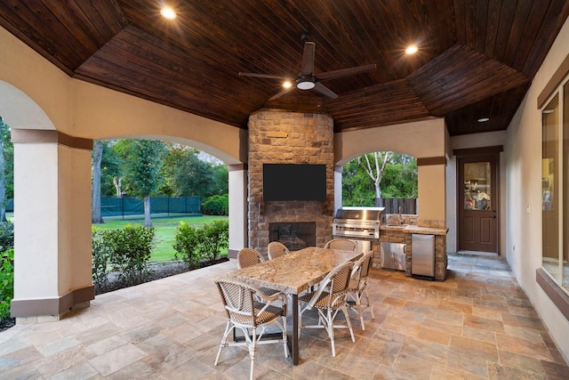 view of patio with an outdoor stone fireplace, area for grilling, a grill, and ceiling fan