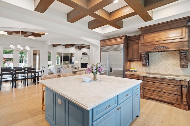 kitchen with stainless steel built in fridge, pendant lighting, light hardwood / wood-style floors, and black electric cooktop